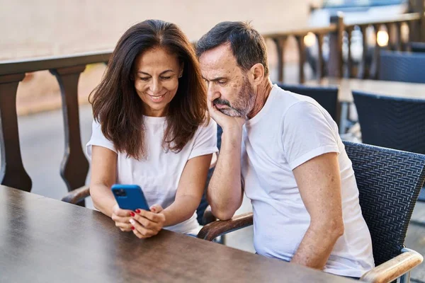 中年男人和女人坐在咖啡店的阳台上 用智能手机交谈 — 图库照片