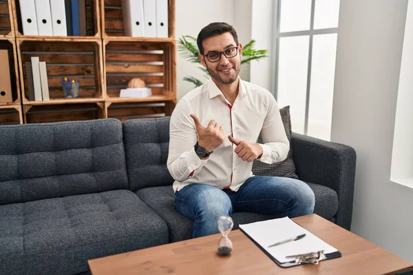 Jovem Hispânico Com Barba Trabalhando Consultório Apontando Para Costas Com — Fotografia de Stock