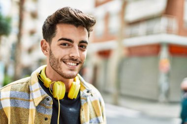 Yakışıklı İspanyol adam, mutlu ve kendine güvenen, kulaklık takan, modern tarzda gülümseyen.