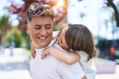 Baba ve kızı gülümsüyor. Parkta birbirlerine sarılıyorlar.