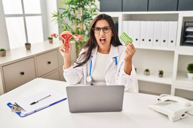 Genç İspanyol doktor kadın elinde anatomik kadın organı ve doğum kontrol hapları tutuyordu. Öfkeliydi, öfkeliydi ve öfkeliydi. Öfkeliydi. öfke ve agresif konsept. 