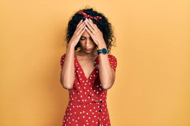 Yazlık elbise giyen genç Latin kız baş ağrısı çekiyor. Acı ve migren yüzünden çaresiz ve stresli. Eller başının üstünde.. 