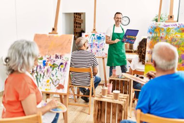 Bir grup orta yaşlı öğrenci resim stüdyosunda resim dersi alıyor..