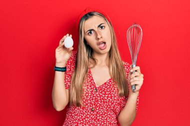 Güzel İspanyol kadın elinde yumurta ve fırıncı fırçasıyla şok olmuş bir halde şüpheli ve alaycı görünüyor, ağzı açık kalınca şaşırıyor. 