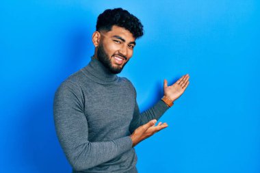 Balıkçı yaka kazak giyen sakallı Arap adam gülümseyerek doğal bir şekilde içeri girmeye davet ediyor. 