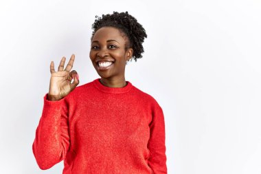 Genç Afrikalı Amerikalı kadın izole edilmiş arka planda günlük giysiler giyip gülümsüyor ve el ve parmaklarıyla 