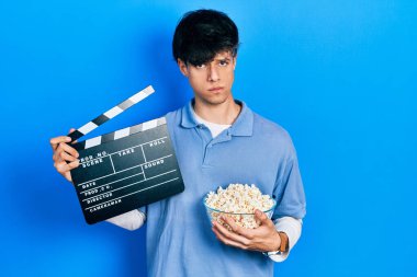 Yakışıklı hippi genç adam patlamış mısır yiyor elinde sinema panosu kuşkucu ve gergin, sorun yüzünden surat asıyor. negatif kişi. 