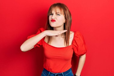 Kırmızı tişört giyen genç bir kadın boğazını bıçak niyetine kesiyor, saldırganlığı şiddetle tehdit ediyor. 