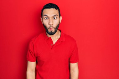 Sakallı, sıradan kırmızı tişörtlü İspanyol adam dudaklı balık suratı yapıyor, çılgınca ve komik bir jest. Komik ifade. 