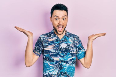 Gündelik kıyafetler giyen genç İspanyol adam zaferi mutlu bir gülümsemeyle ve kazanan yüz ifadesiyle kutluyor. 