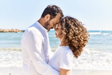 Orta yaşlı İspanyol çift sahilde sarılıyor..