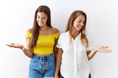 Anne ve kızı yalıtılmış arka planda yan yana durup gülümseyerek avuçlarını açık tutuyor, karşılaştırma ve reklam karşılaştırması yapıyor ve dengeyi sağlıyor. 