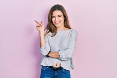 Gündelik giysiler giymiş genç beyaz kız gülümsüyor mutlu bir şekilde elini ve parmağını yana uzatıyordu. 