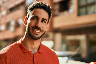 Genç İspanyol adam gülümseyerek şehirde mutlu mesut dikiliyor..