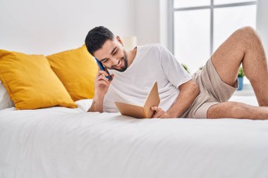 Genç Arap adam yatak odasında akıllı telefon okuyarak konuşuyor.