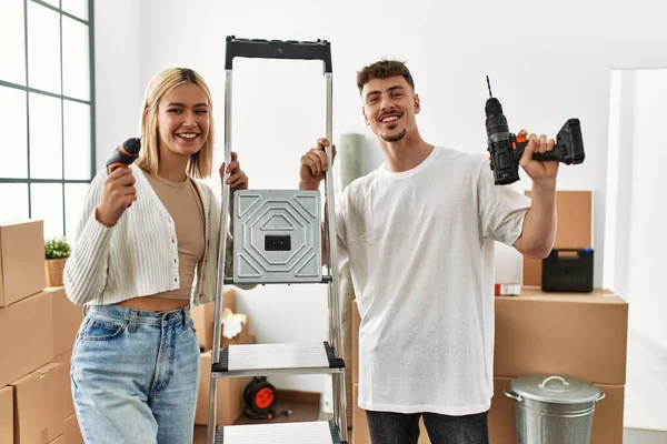 Genç beyaz çift mutlu bir şekilde gülümsüyor işçi merdivenlerini tutuyor ve yeni evlerinde talim yapıyor..