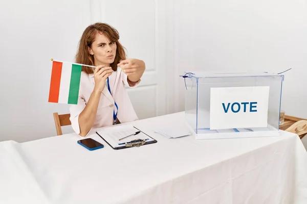 Beautiful caucasian woman at political campaign election holding hungary flag pointing with finger to the camera and to you, confident gesture looking serious