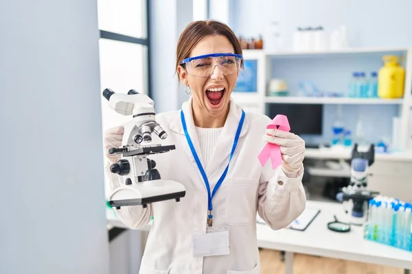 Young Brunette Woman Working Scientist Laboratory Holding Pink Ribbon Winking — Photo