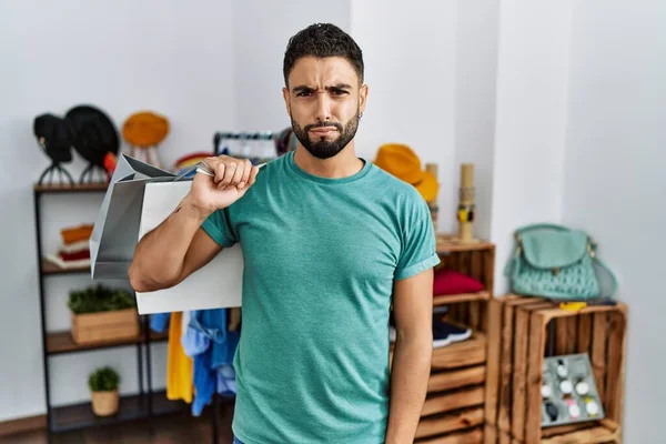Mağazada sakallı, alışveriş torbası tutan yakışıklı bir genç. Depresyonda ve üzüntüden ağlıyor, ağlıyor ve korkuyor. hüzünlü ifade. 