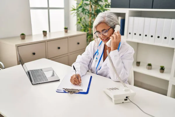 身着医生制服的中年妇女在诊所电话交谈 — 图库照片