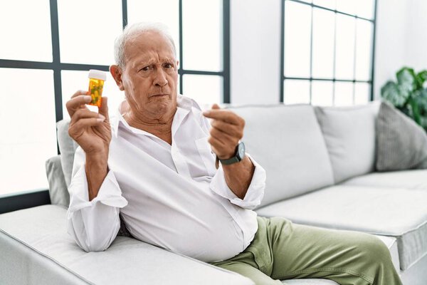 Senior man holding pills doing money gesture with hands, asking for salary payment, millionaire business 