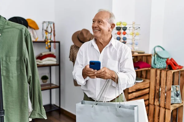 Senior man customer using smartphone at clothing store