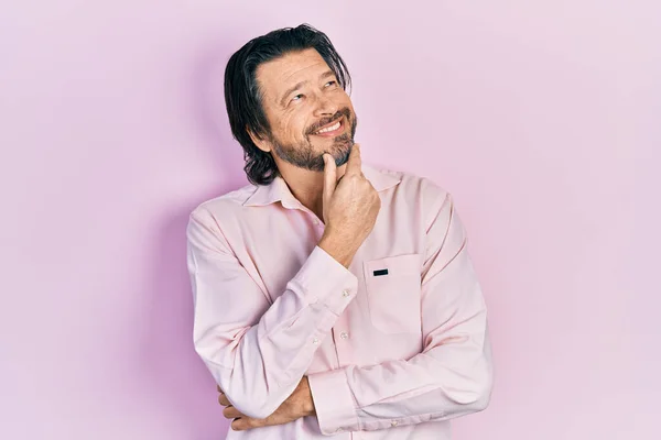 Middle age caucasian man wearing casual clothes looking confident at the camera with smile with crossed arms and hand raised on chin. thinking positive.