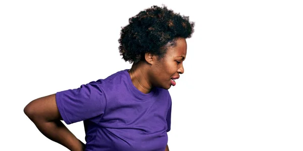 アフリカ系アメリカ人の女性は 背中の痛みに苦しんで 手で背中に触れ 筋肉痛のカジュアルな紫色のTシャツを着て — ストック写真