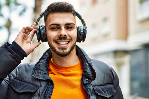 Sakallı yakışıklı, neşeli ve kendine güvenen, kışlık palto ve kulaklık takan bir İspanyol.