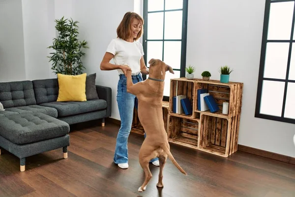Young caucasian woman smiling confident dancing with dog at home