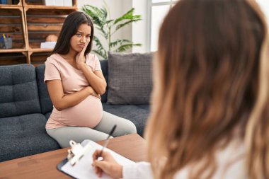 Terapi seansında genç hamile bir kadın kollarını kavuşturarak depresyondan yorgun ve sıkılmış göründüğünü düşünüyor.. 