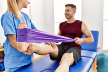Genç İspanyol fizyoterapist kadın klinikteki adama bacak rehabilitasyonu yapıyor..