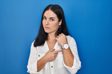 Mavi arka planda dikilen genç İspanyol kadın zamanı, sabırsızlığı ve rahat bir ifadeyle kameraya bakmayı işaret ediyor. 