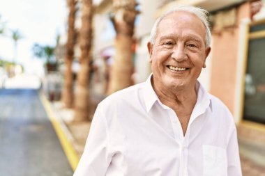 Güneşli bir günde kır saçlı son sınıf öğrencisi dışarıda mutlu mesut dikiliyor. Emeklilik için 70 'lerinde mutlu bir gülümseme.