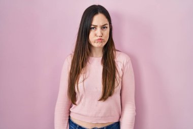 Pembe arka planda duran esmer bir kadın komik yüzüyle yanaklarını şişiriyor. Havayla şişmiş ağız, çılgın bir ifade.. 