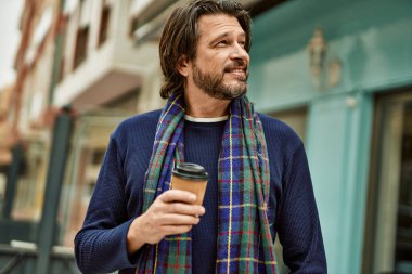 Orta yaşlı yakışıklı adam kasabada bir fincan kahve içiyor.