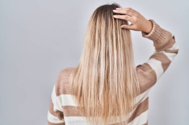 Balıkçı yaka kazak giyen genç sarışın kadın izole edilmiş arka planda geriye doğru, elleri kafasında şüpheyi düşünüyor. 