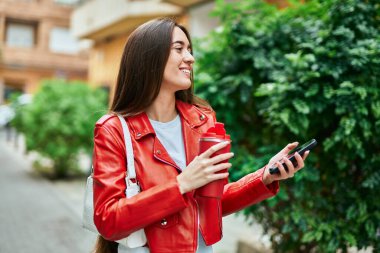 Genç İspanyol kadın akıllı telefon kullanıyor ve şehirde kahve içiyor..