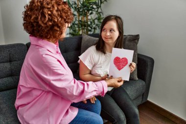 Olgun anne ve Down sendromlu kız evde, bir kadın annesine anneler günü aşk kartı veriyor.