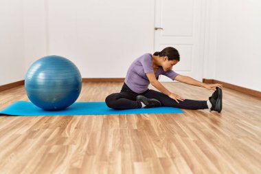 Genç Latin kadın spor merkezinde formda top kullanarak esniyor.