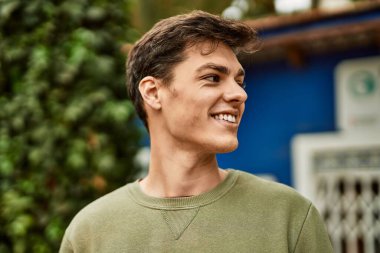 Genç İspanyol adam gülümseyerek şehirde mutlu mesut dikiliyor..