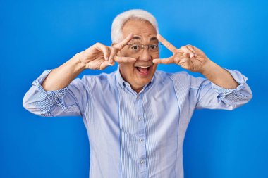 İspanyol kıdemli gözlüklü, barış sembolü takan, yüzünde parmakları olan, gülümseyen, zafer gösteren bir adam. 