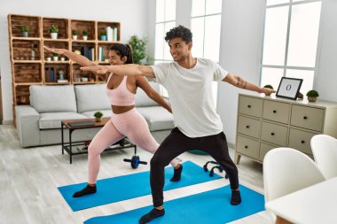 Genç Latin sporcu çift gülümseyerek evde mutlu bir antrenman yapıyor..