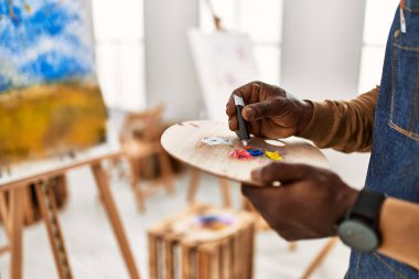 Palet sanat stüdyosunun rengini karıştıran Afrikalı Amerikalı sanatçı..
