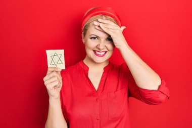 Sarışın, elinde Yahudi yıldızı olan genç bir kadın hatırlatıcısı. Elleri başının üstünde, şaşırmış ve kızgın bir yüzle. 