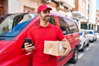 Genç İspanyol kurye sokakta akıllı telefon paketi kullanıyor.