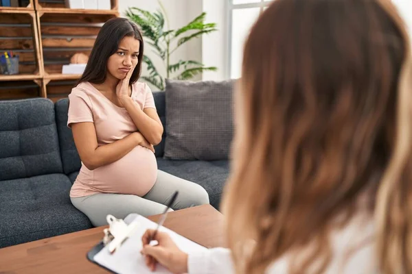 Terapi seansında genç hamile bir kadın kollarını kavuşturarak depresyondan yorgun ve sıkılmış göründüğünü düşünüyor.. 
