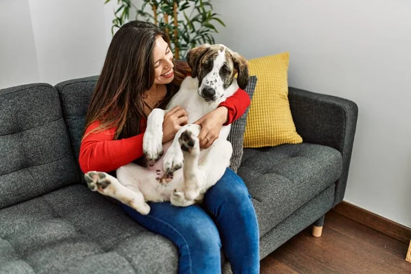 Young woman hugging dog sitting on sofa at home