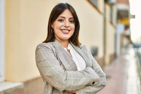 Genç İspanyol iş kadını şehirde çapraz hareketlerle mutlu gülümsüyor..