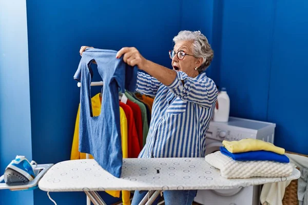 洗濯室で焼かれた鉄のシャツを着たシニア白髪の女性 — ストック写真